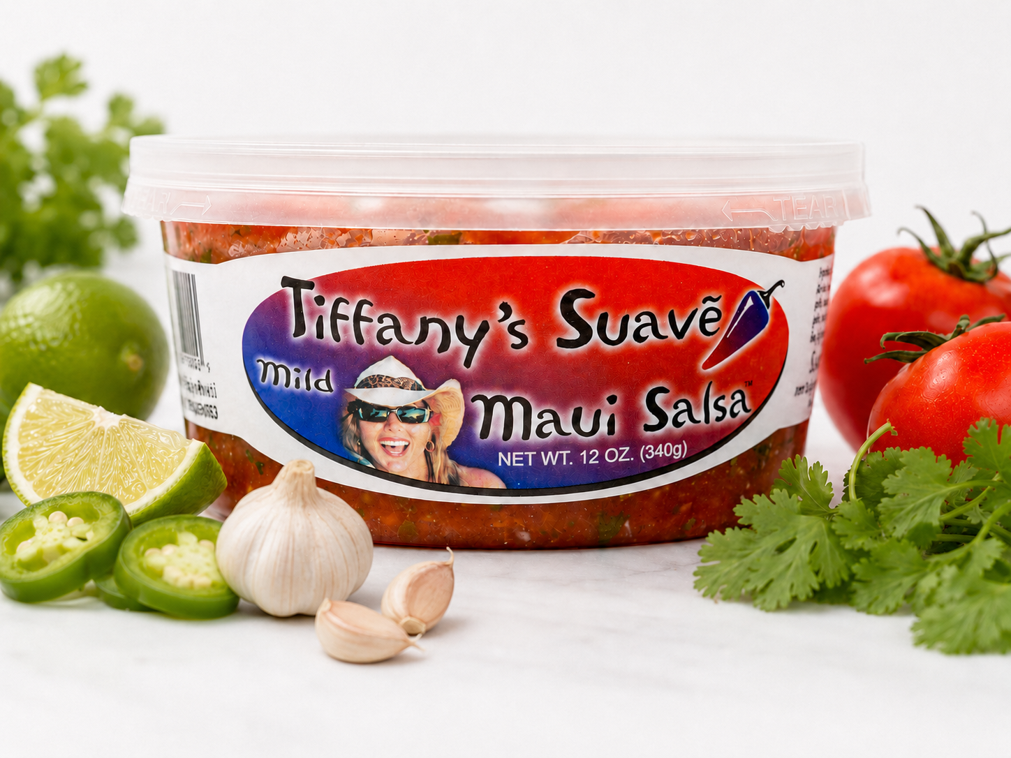 A 12 oz tub of Tiffany's Suavē Maui Salsa styled with fresh produce