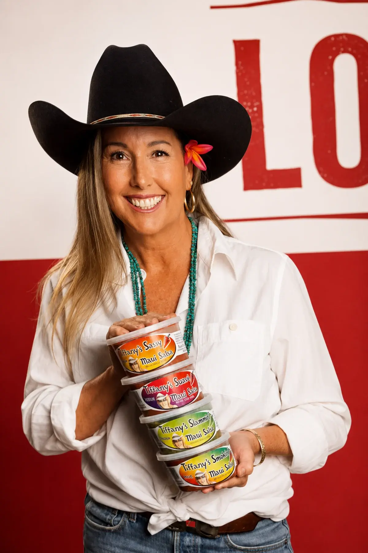 Tiffany Smith in a black cowboy hat, holding all four tubs of Tiffany's Sassy Maui Salsa